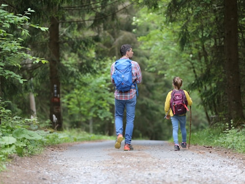 man in blue jacket and blue denim jeans walking on dirt road during daytime